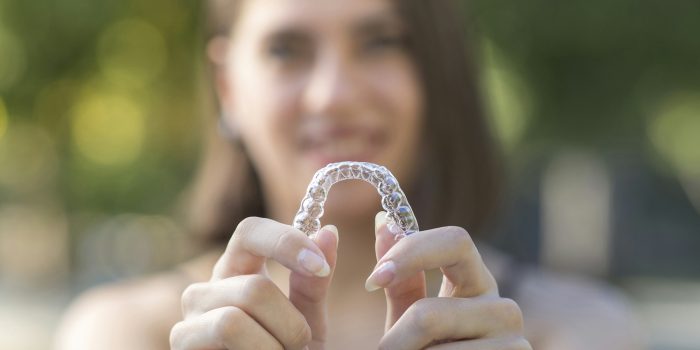 Beautiful smiling Turkish woman is holding an invisalign bracer