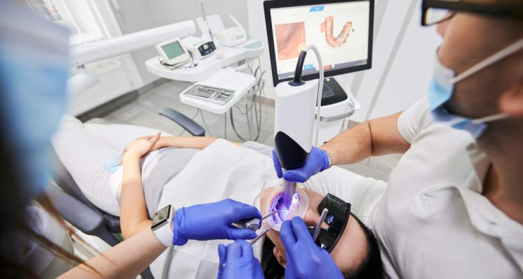 Doctor scanning patient mouth with modern intraoral scanner.