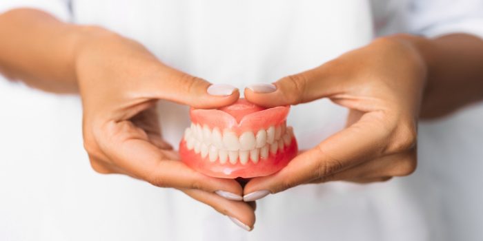 The dentist is holding dentures in his hands. Dental prosthesis in the hands of the doctor close-up